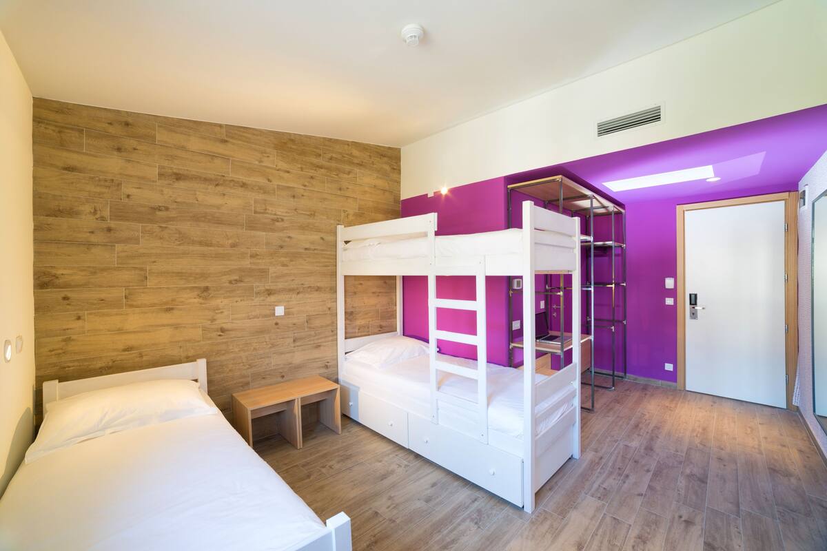 A room with a bunk bed, a desk, and a wardrobe.