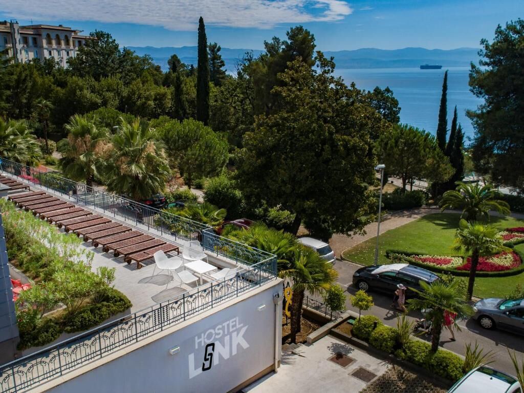 A hostel with outdoor seating, a view of the sea, and a well-maintained garden.