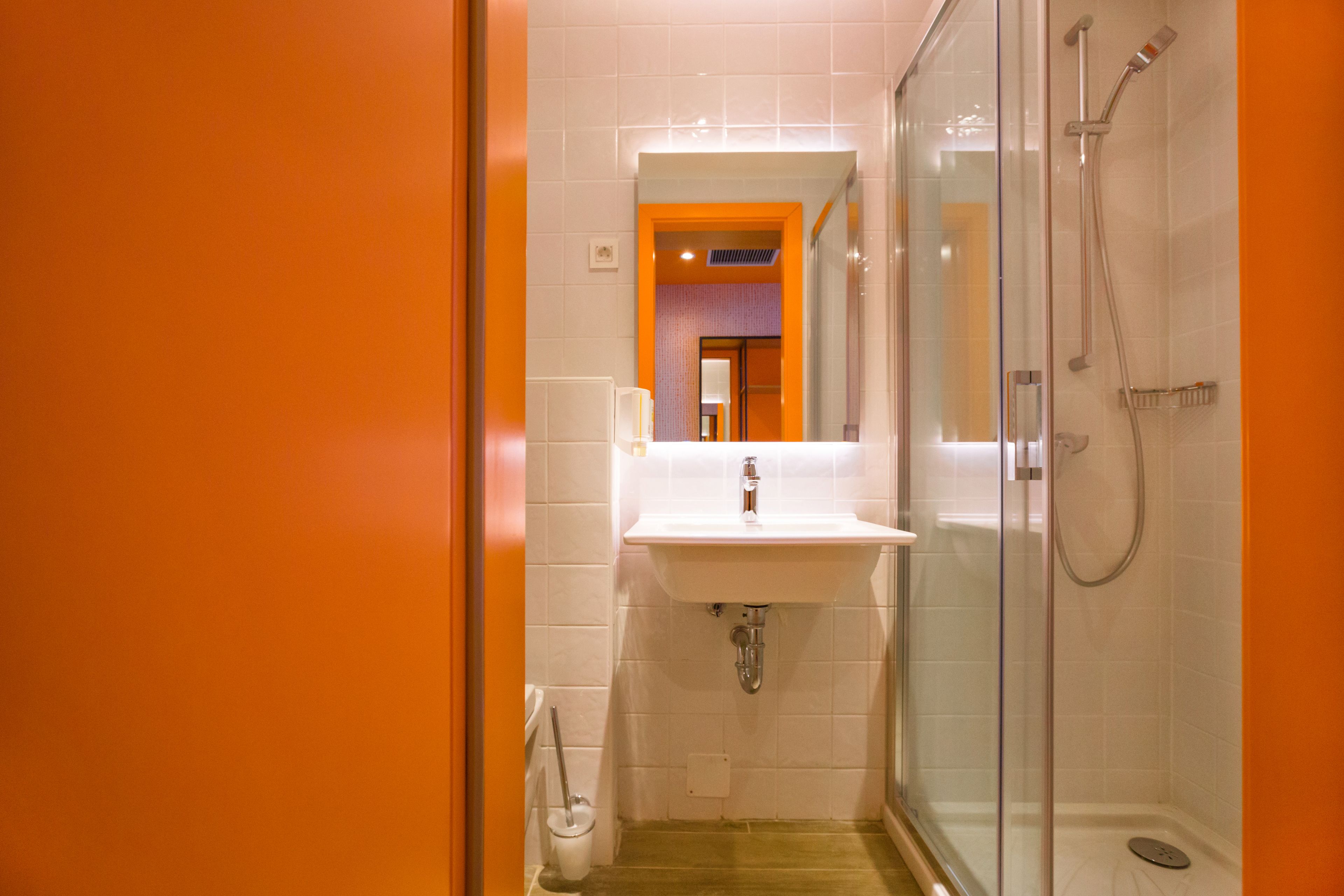 Une salle de bain moderne avec une douche à parois de verre, un lavabo blanc et un miroir au-dessus du lavabo.