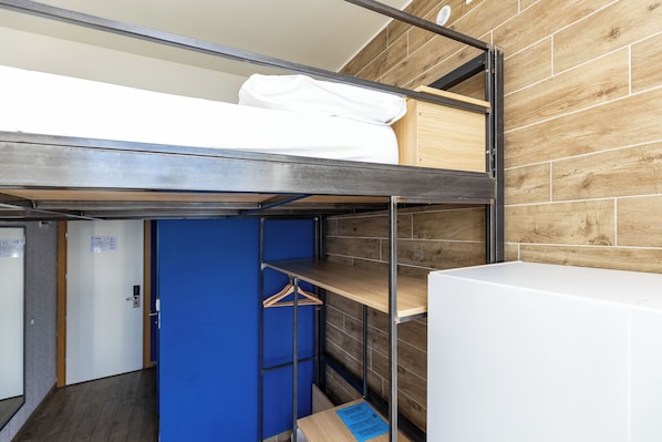 A bunk bed room with a wooden wall, a blue door, and a white wardrobe. - Hostel Link (Lovran)