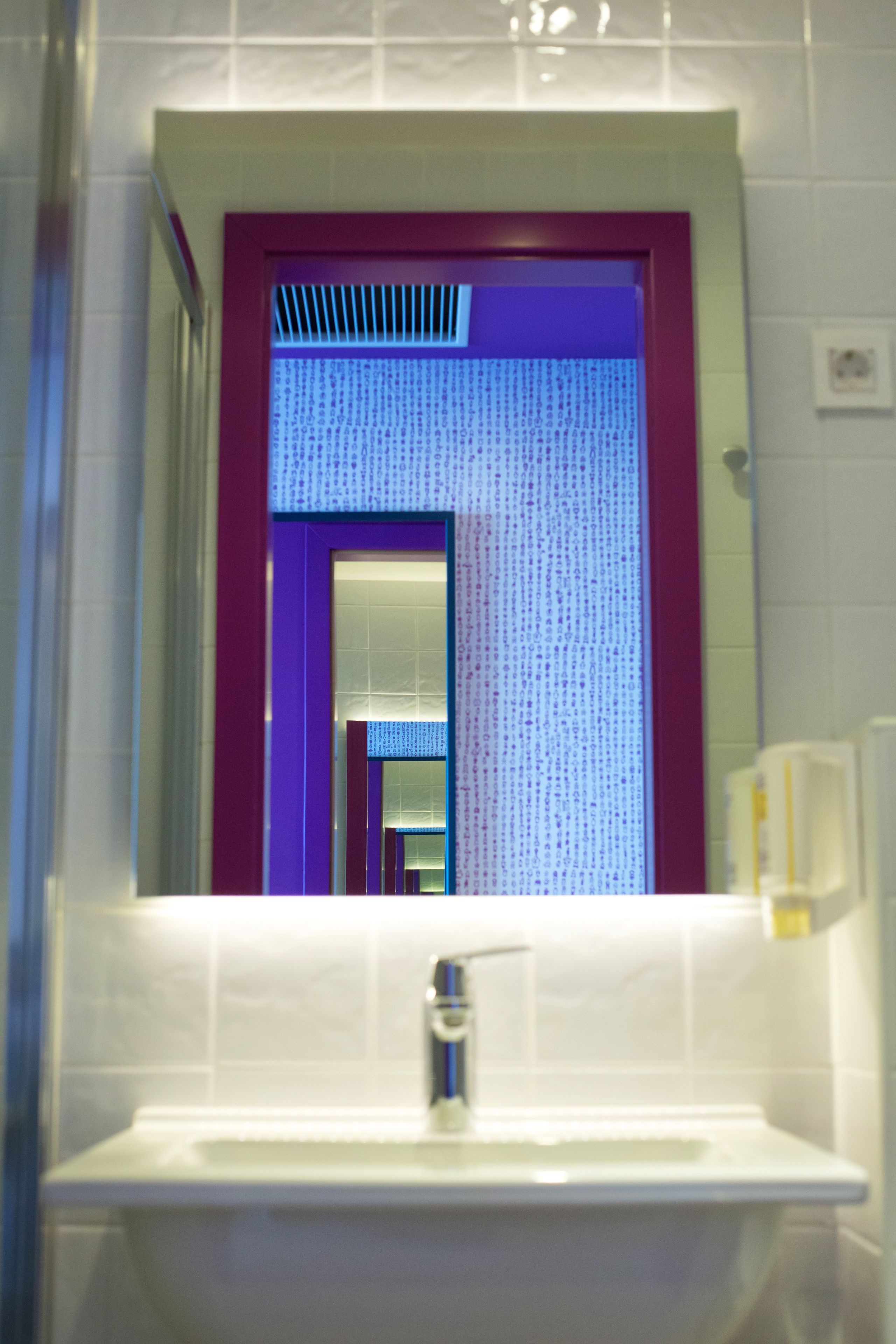 A bathroom with a mirror, sink, and a tiled wall.