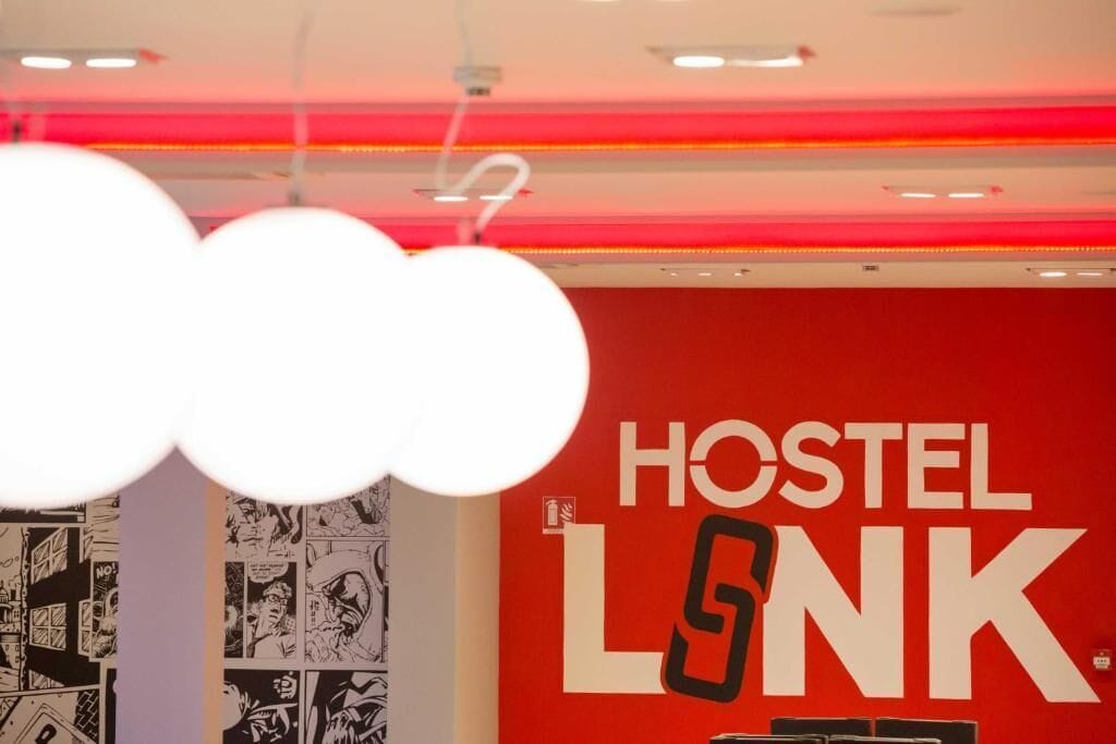 Una pared roja con el texto "HOSTEL LNK" y una tira cómica a la izquierda.