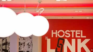 Una pared roja con el texto "HOSTEL LNK" y una tira cómica a la izquierda.