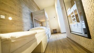 Ein modernes Hotelzimmer mit Etagenbett, Holzboden und großem Fenster.
