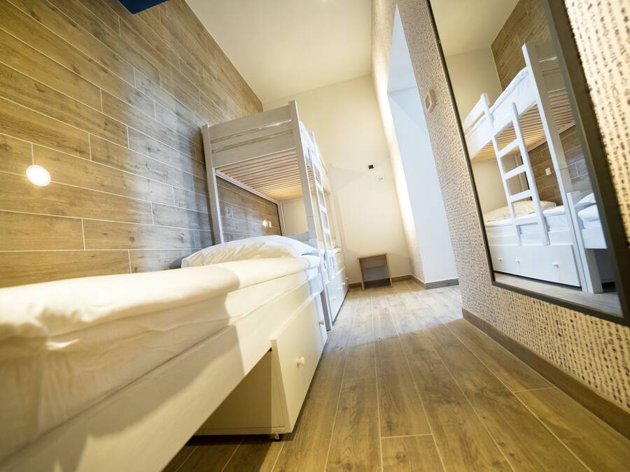 Ein modernes Hotelzimmer mit Etagenbett, Holzboden und großem Fenster.