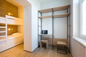 Una habitación compacta con literas, un escritorio con silla y estanterías.