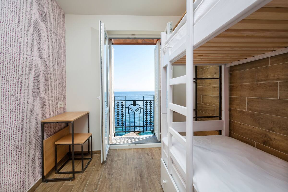 A balcony with a wooden floor and a view of the sea.