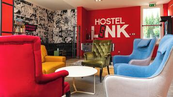 A modern hostel interior with vibrant red walls, a comic strip mural, and colorful seating.