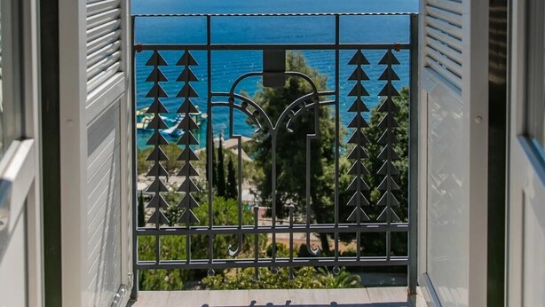 A balcony with a metal railing and a view of the sea. - Hostel Link  (Lovran)