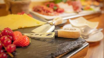A cheese board with various cheeses and fruits.
