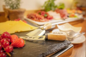 A cheese board with various cheeses and fruits.