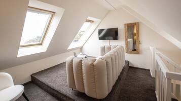 A modern room with a large window, a flat-screen TV, and a unique seating arrangement.