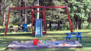 A playground with a swing set, slide, and picnic table.