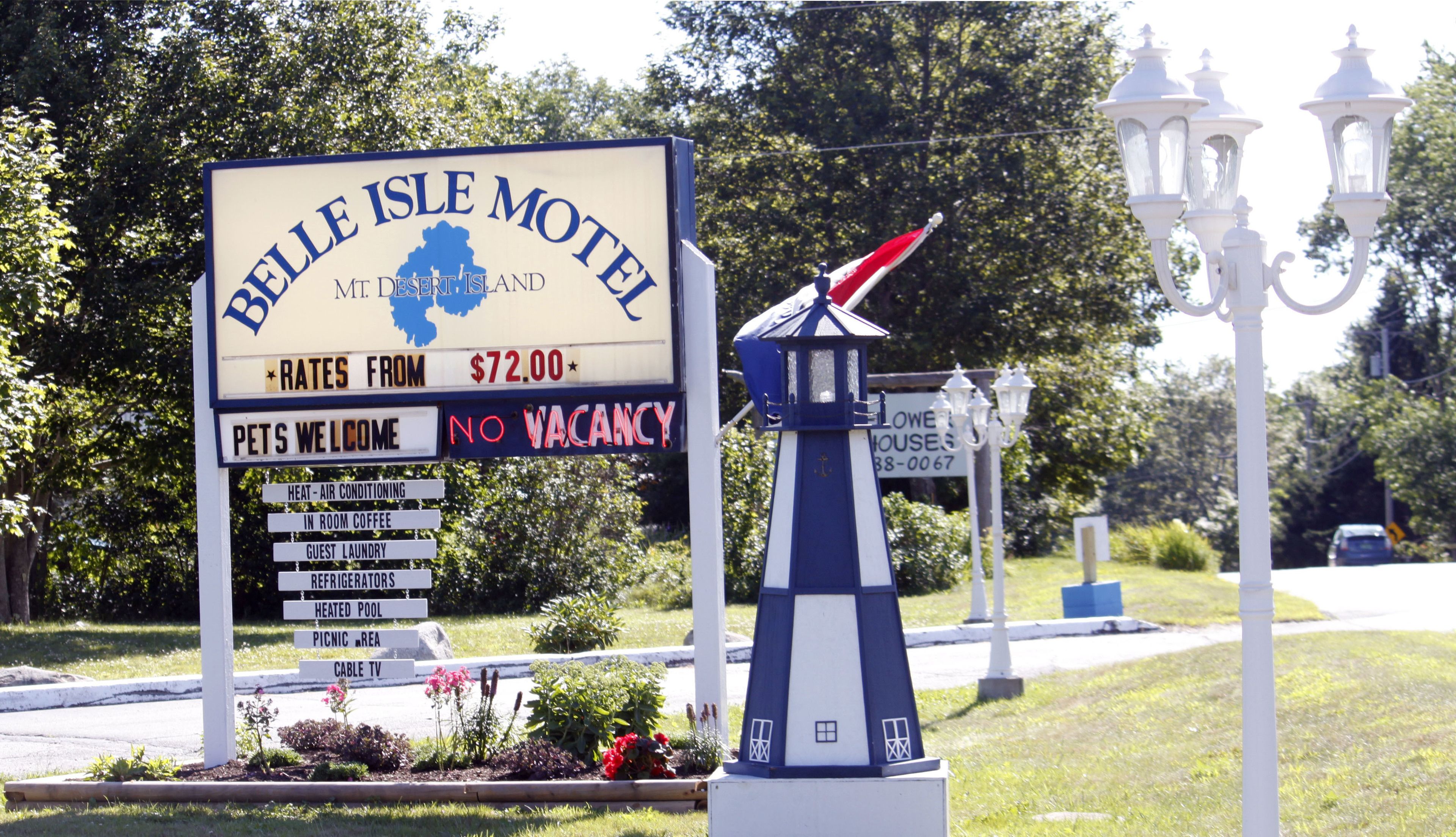 A Belle Isle Motel sign with amenities like heat, air conditioning, in-room coffee, guest laundry, and a heated pool.