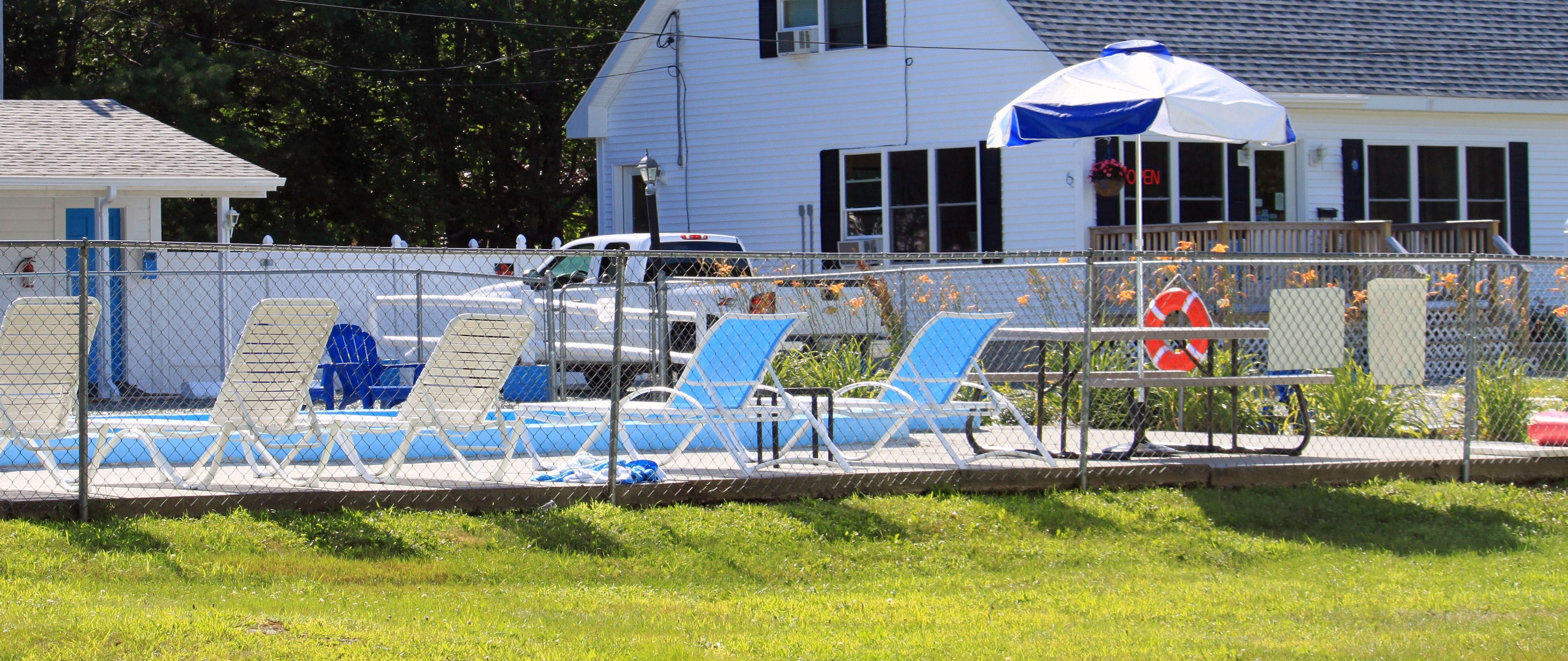 A fenced swimming pool area with lounge chairs and a lifebuoy.