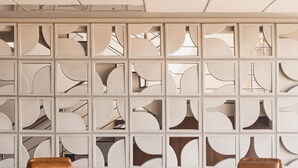 A modern interior with two leather chairs, a small table with a vase, and a decorative wall with geometric patterns. -  Strassen Hotel (Aparecida de Goiania)