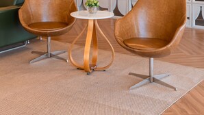 A modern lobby with two brown leather chairs, a small round table, and a decorative wall with geometric patterns. -  Strassen Hotel (Aparecida de Goiania)