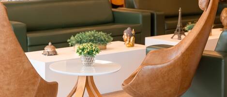 A modern lounge area with green sofas, a white coffee table with decorative items, and unique wooden chairs.