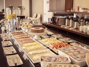 A buffet with various food items, including pastries, meats, and dairy products.