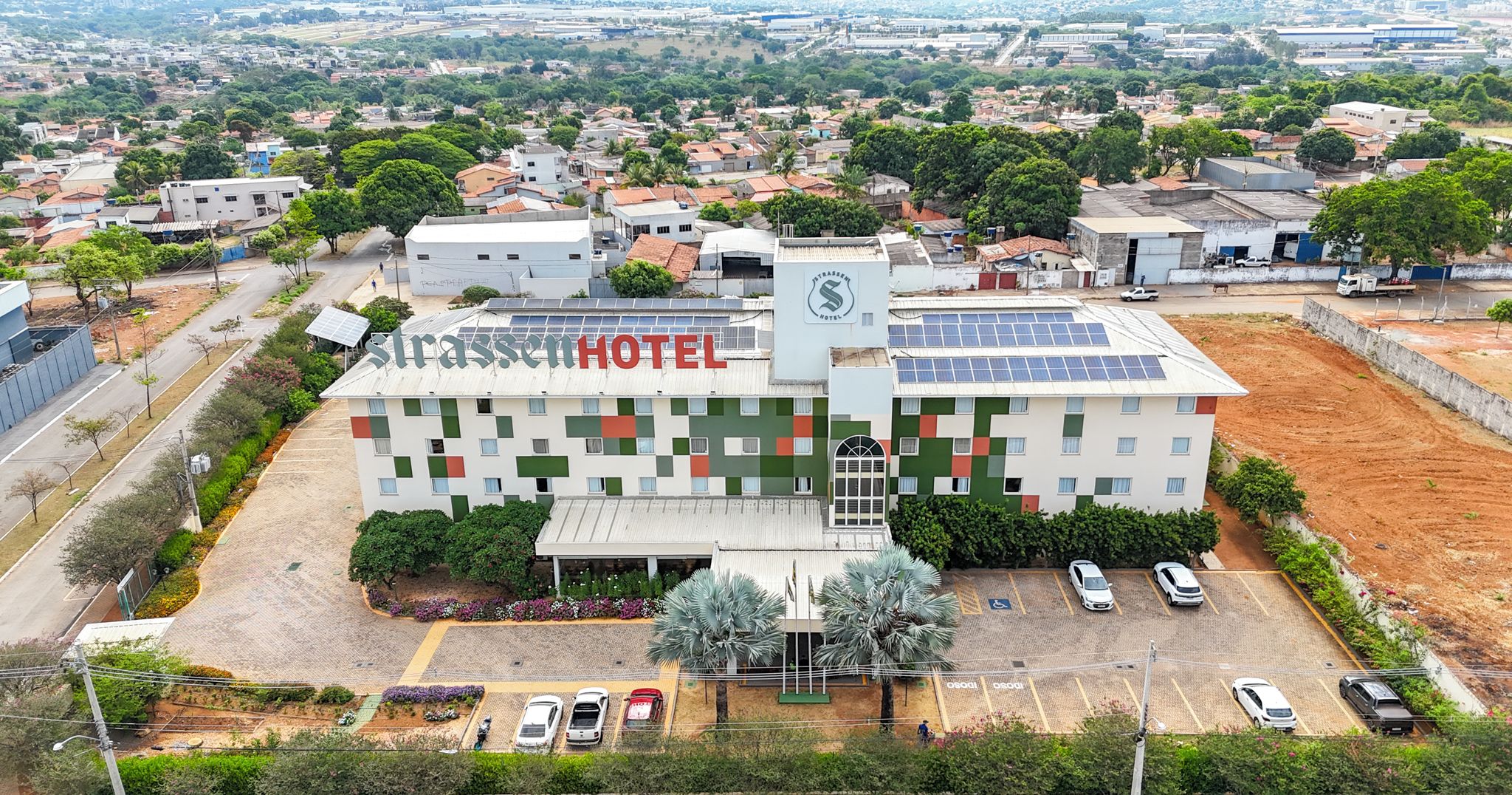 A hotel with a modern design, solar panels, and a parking lot.