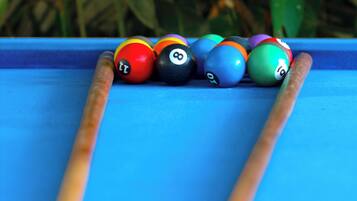 Een pooltafel met ballen en stokken.