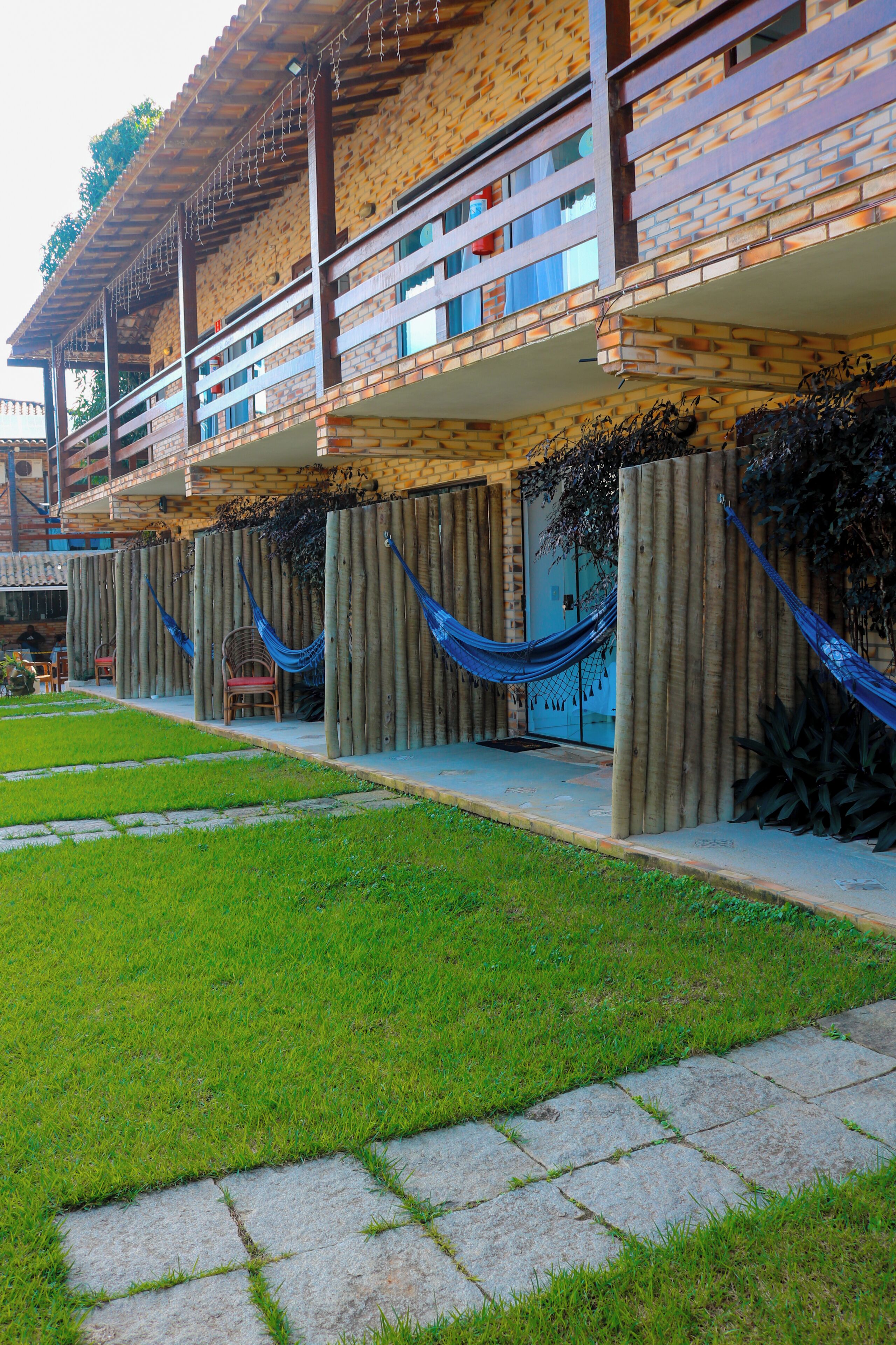 Un edificio con fachada de ladrillo, varios balcones y un área verde al frente.