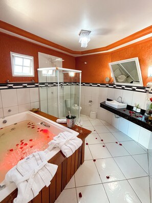 A bathroom with a bathtub, shower, vanity, and a large mirror.
