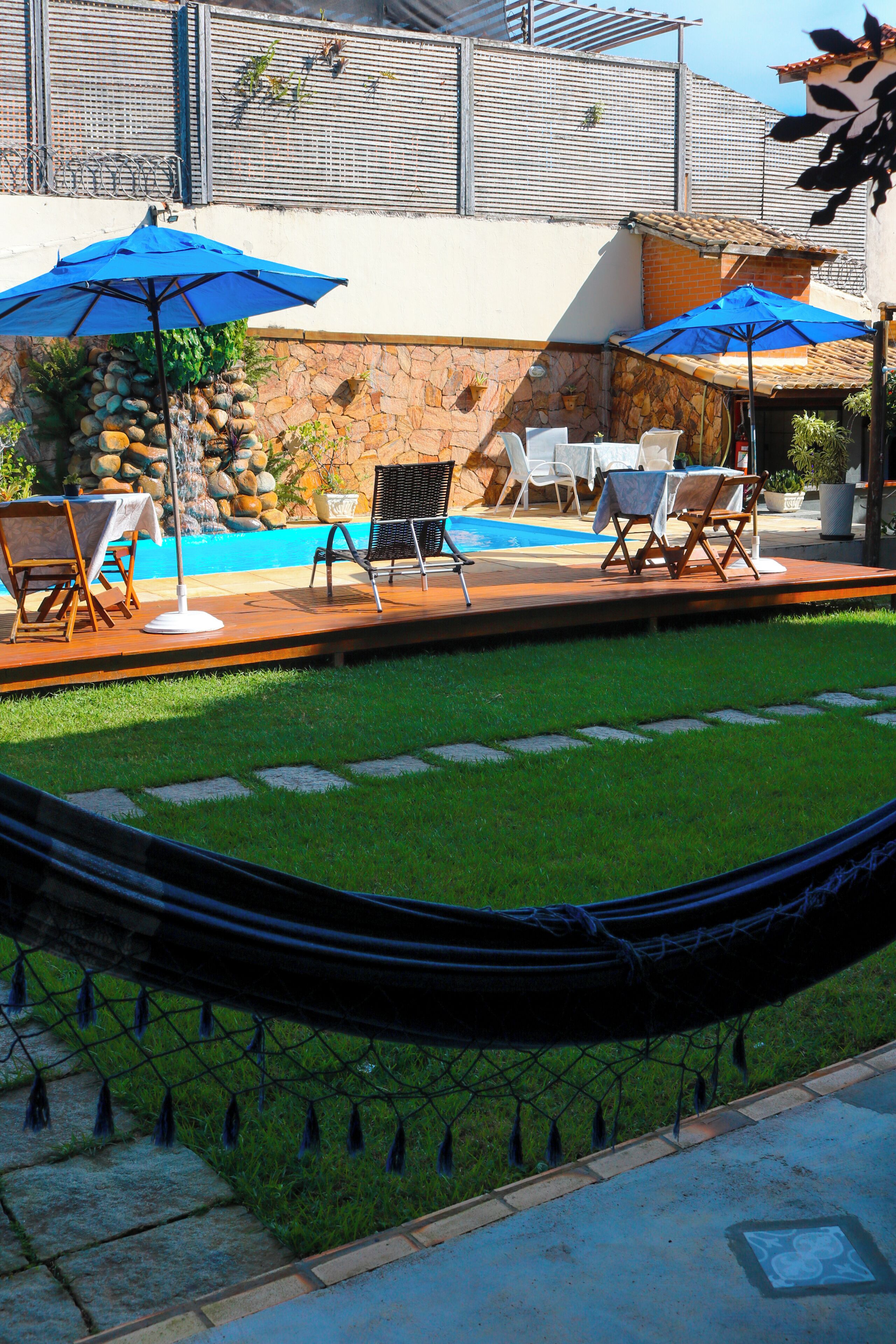 A pool area with lounge chairs, umbrellas, and a hammock.