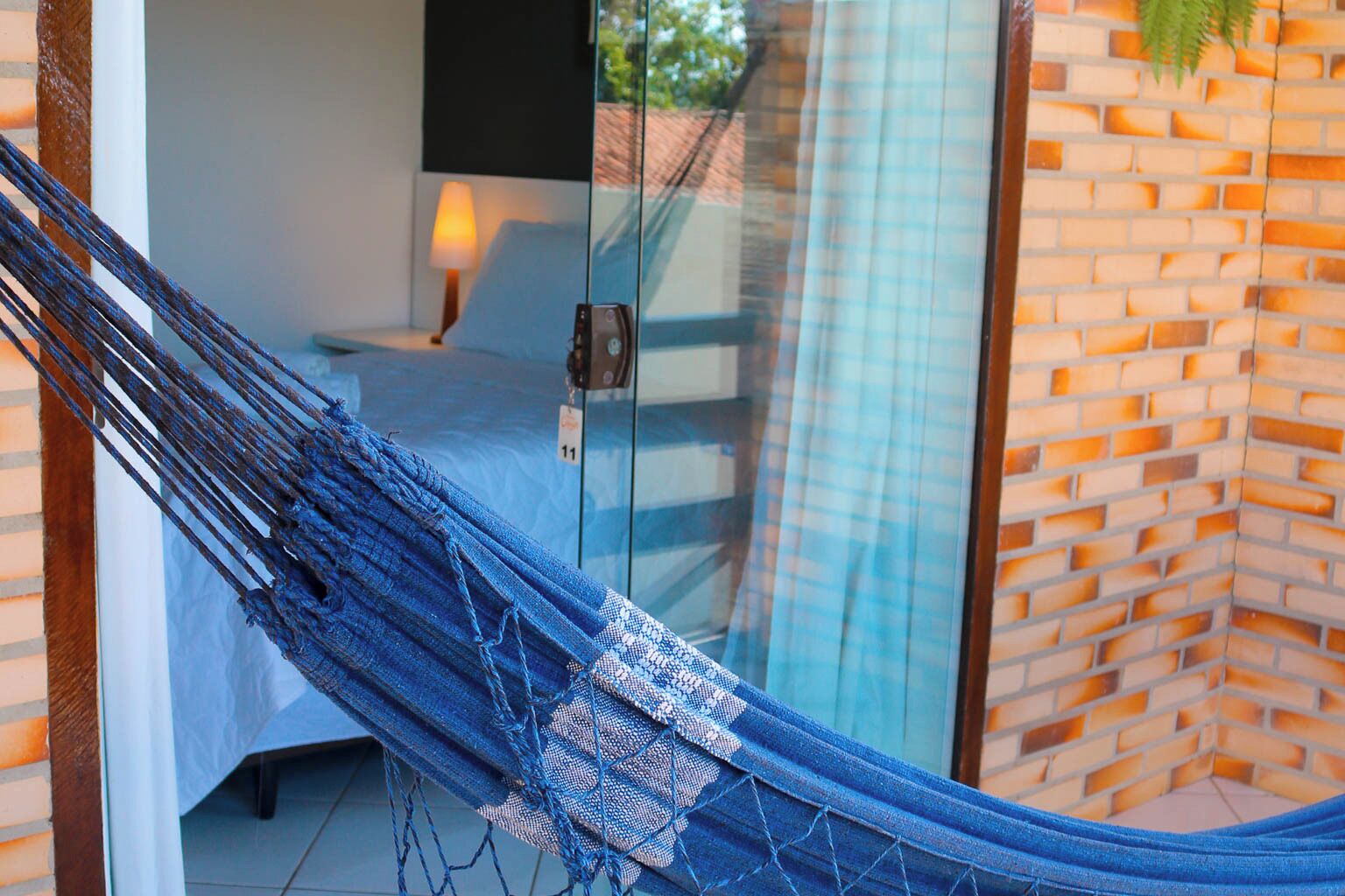 Una hamaca en una habitación con puerta de vidrio, una cama y una lámpara.