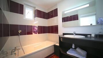Een moderne badkamer met een bad, een wastafel en een spiegel.