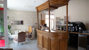 Una sala de estar con una mesa de centro de madera, un sofá y una silla. Cuenta con una zona de cocina con cafetera y lavavajillas.