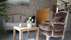 Una sala de estar con un sofá, una mesa de centro de madera y un sillón con cojines.