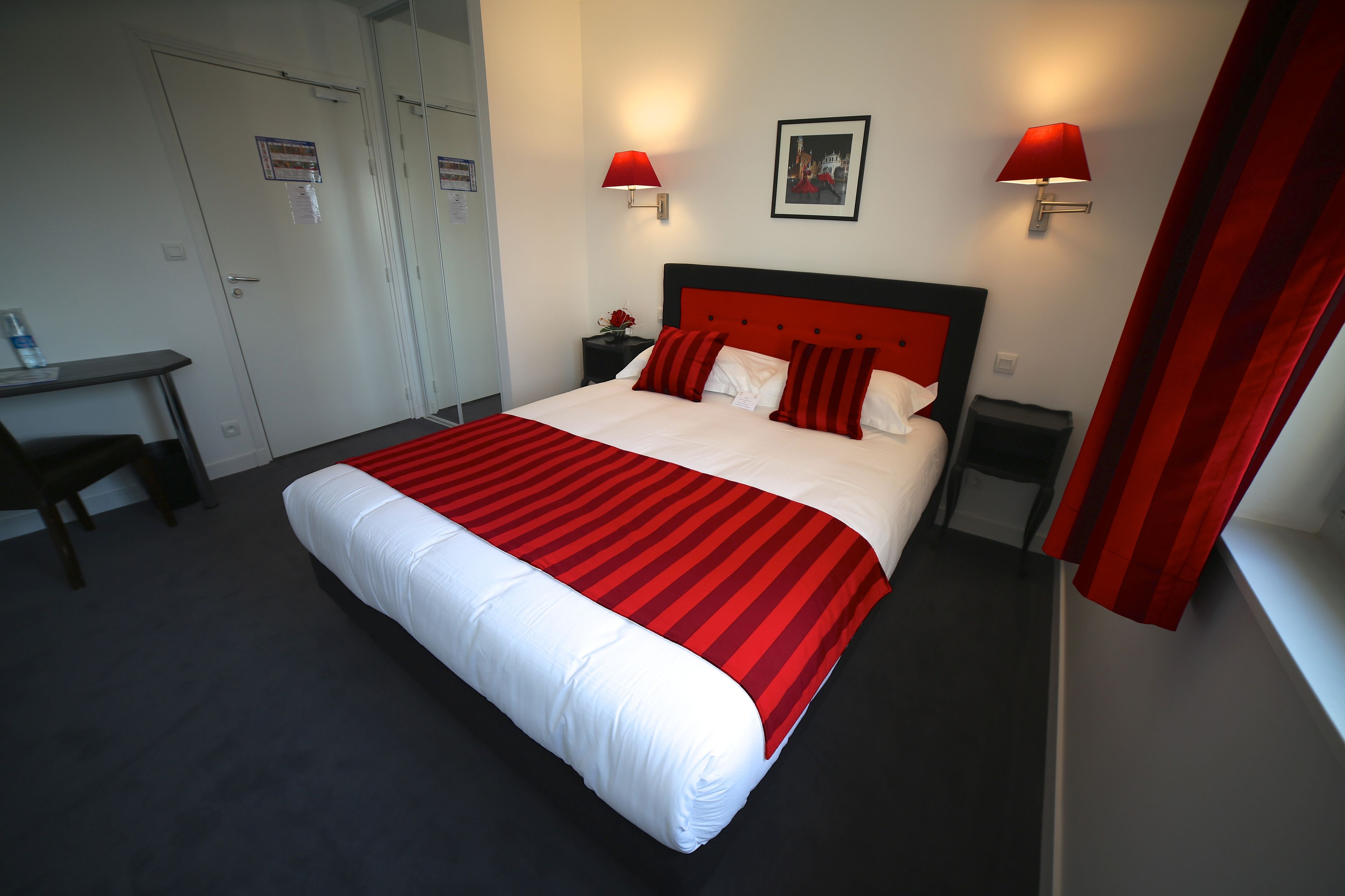 Een hotelkamer met een groot bed, twee nachtkastjes, een bureau en een stoel.