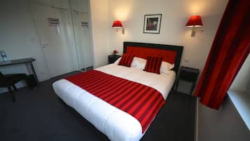 Ett hotellrum med en stor säng, två sängbord, ett skrivbord och en stol.