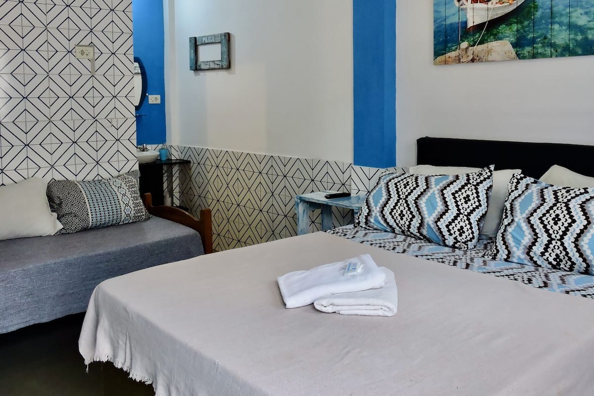 Un dormitorio con cama, mesita de noche, lámpara colgante, un cuadro en la pared y un papel tapiz decorativo.