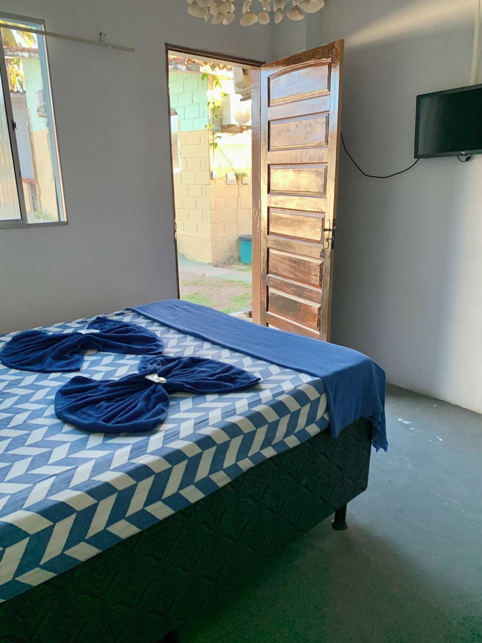 A room with a bed, a television mounted on the wall, and a door leading to an outdoor area.