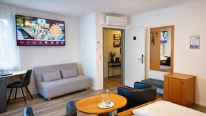 Ein Hotelzimmer mit einem Bett, einem Sofa, einem Schreibtisch und einem Fernseher, der eine Speisekarte zeigt.