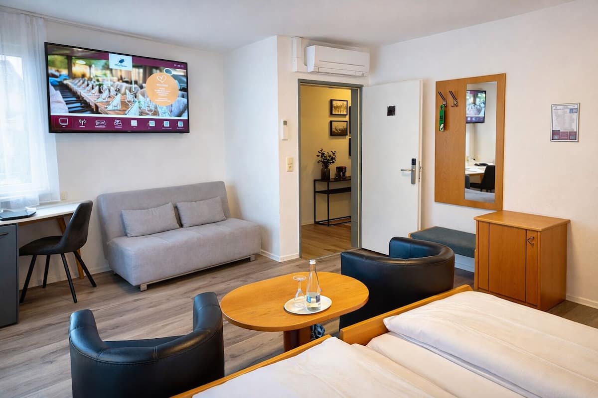 Une chambre d’hôtel équipée d’un lit, d’un canapé, d’un bureau et d’une télévision qui affiche le menu d’un restaurant.
