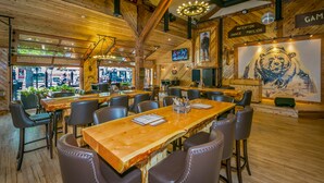 Een ruim restaurant met houten inrichting, meerdere tafels en stoelen.