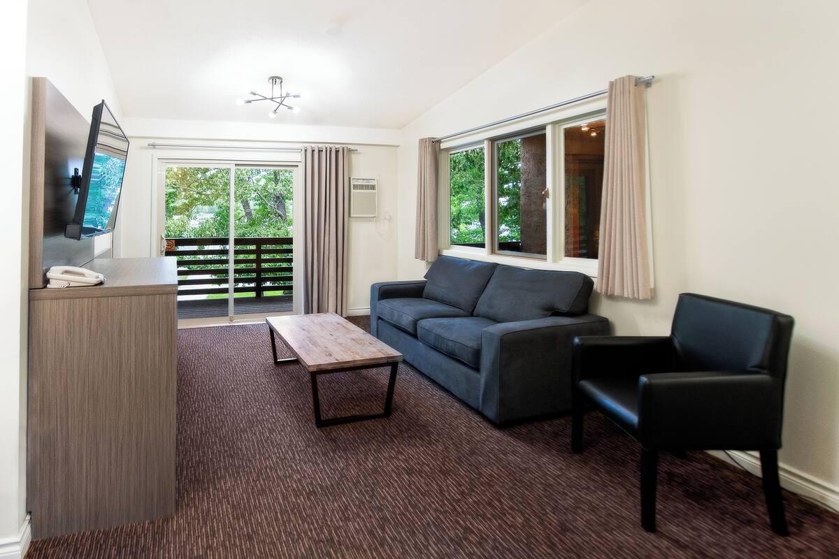 A modern living room with a sofa, a coffee table, a TV, and a desk with a telephone.