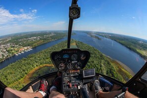 Cabina de helicóptero con vistas a un río y el paisaje circundante.