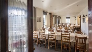 Ein Restaurant mit mehreren Tischen und Stühlen, einer Steinsäule und einer Tür mit gefrostetem Glas.
