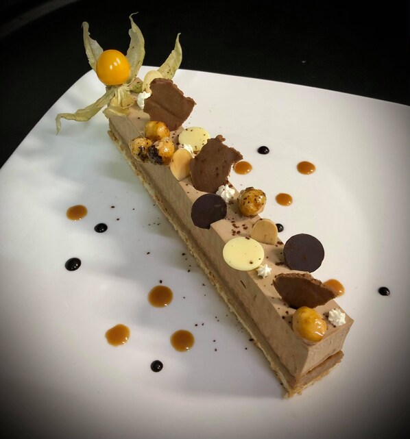 A dessert on a white plate with various toppings and sauces. - Hotel Le Mercier (Mont-Tremblant)