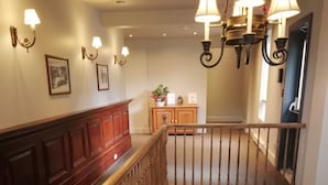 Eine Treppe mit Holzgeländern und Handlauf, die zu einer oberen Etage führt.