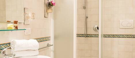 A bathroom with a glass-enclosed shower, a sink, a toilet, and a bidet.