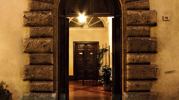 Un arco de entrada que da a un edificio con una puerta de madera y una escalera.