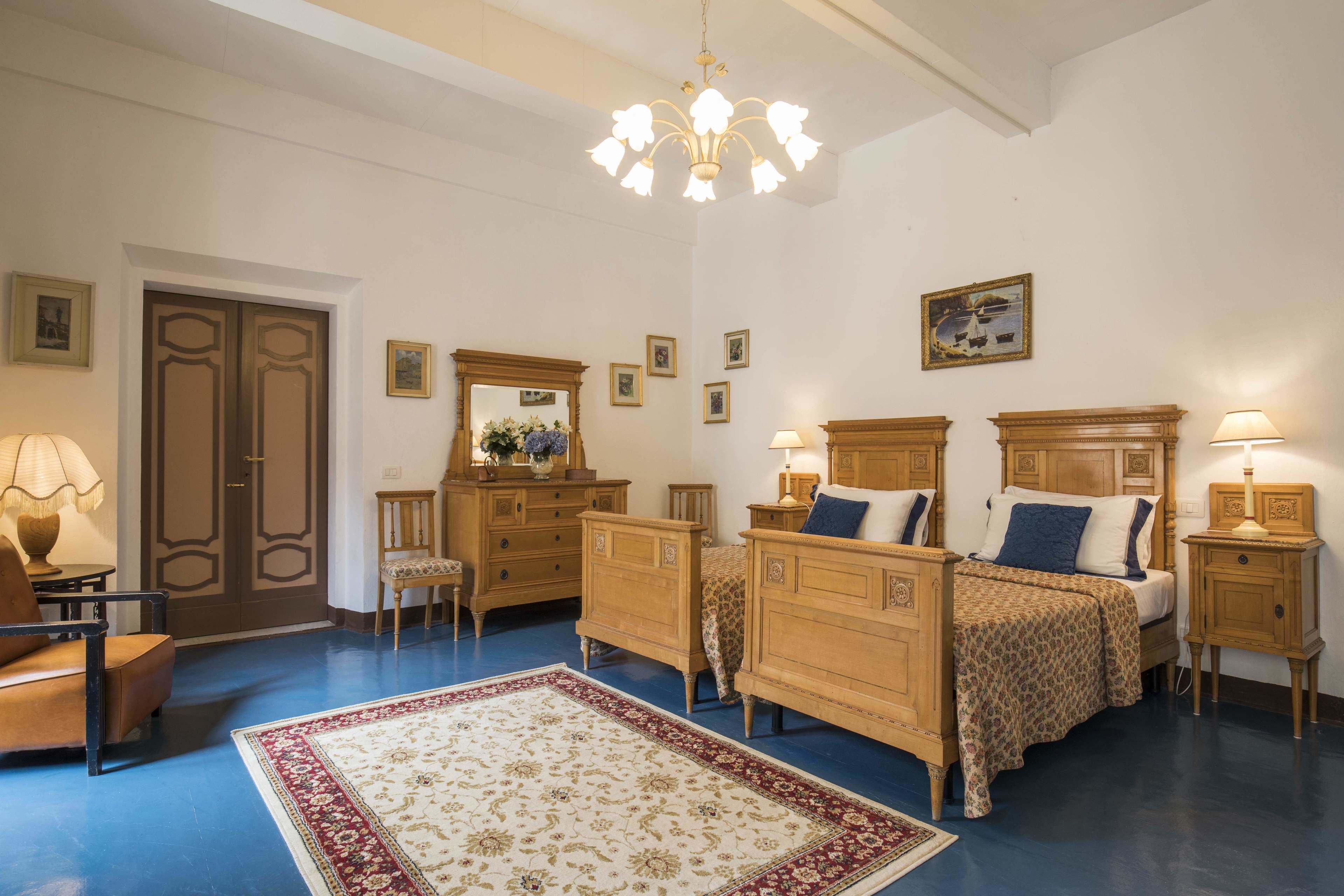 A bedroom with a large bed, two bedside tables, a chair, a dresser, and a mirror.