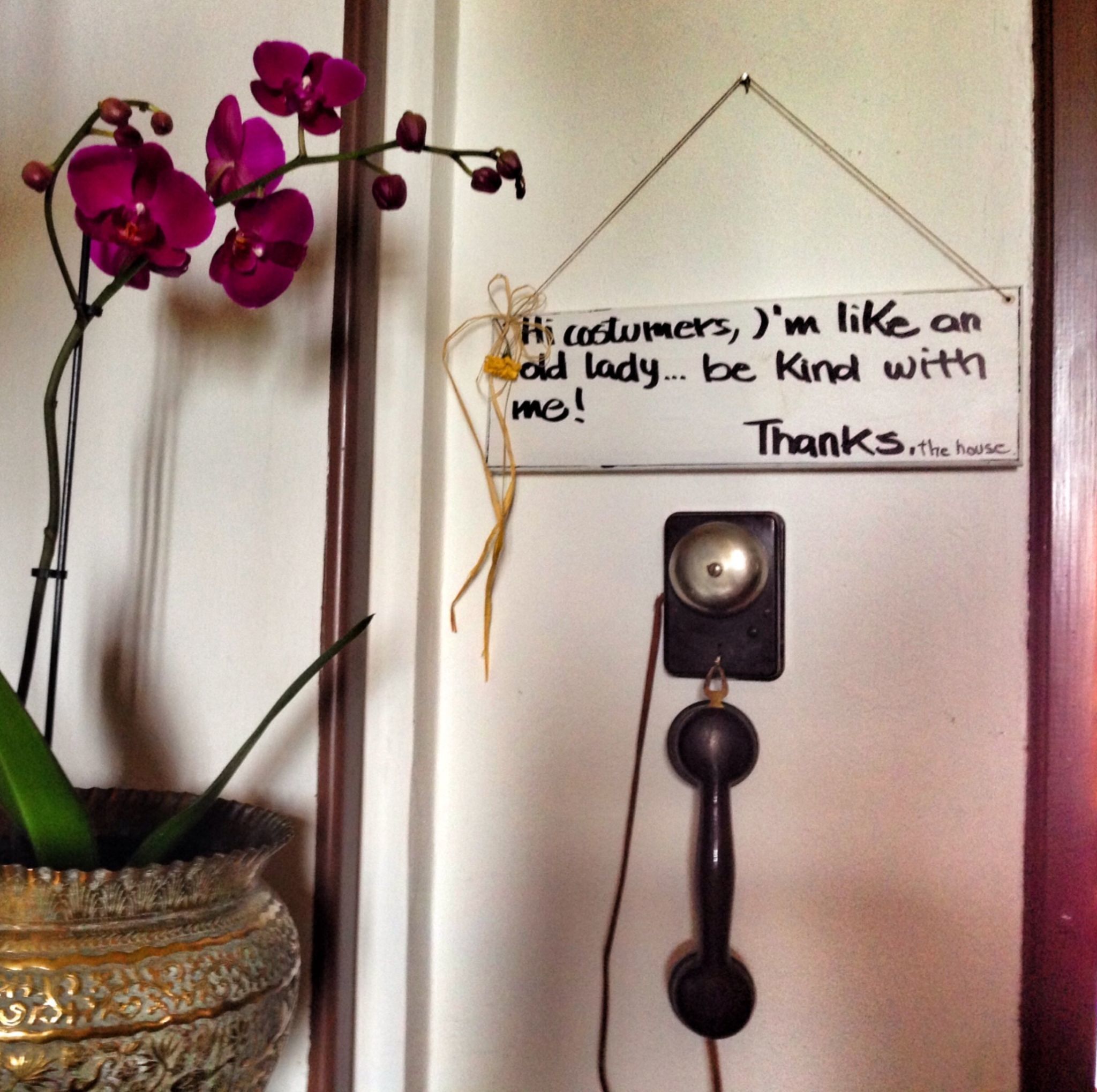 A door with a sign that reads "Hi costumers, I'm like an old lady... be kind with me! Thanks, the house."
