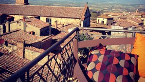 Un balcón con vistas a un pueblo, que incluye una torre de iglesia y montañas a lo lejos.