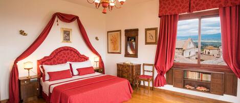 Un dormitorio con cama con dosel, muebles de madera, vistas al campo y una araña.